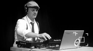 DJ Dominick zwart wit foto achter de draaitafels.